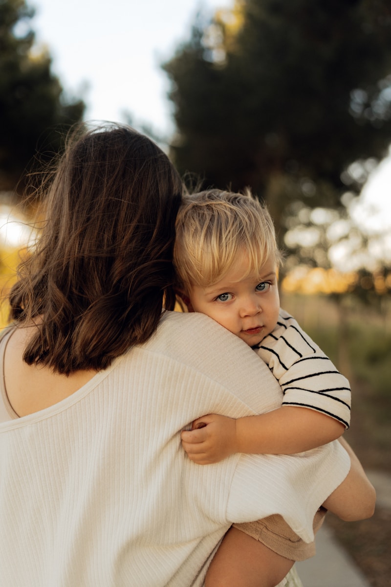 Mother holding her blond-haired baby outdoors